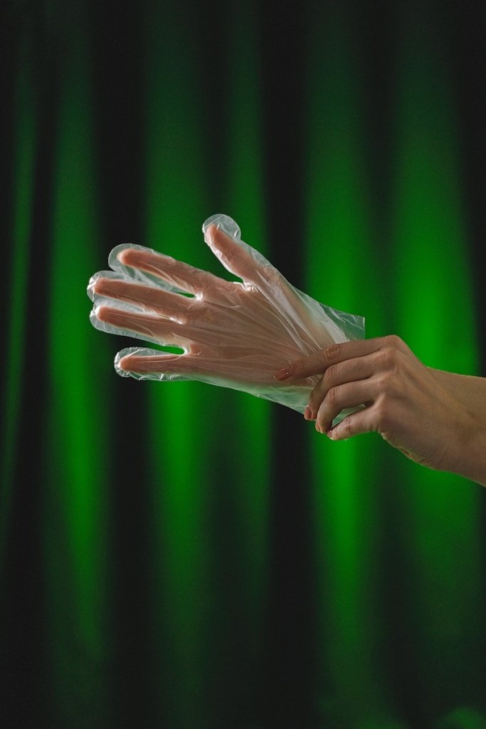 Close-Up Photo of a Person's Hands Putting on a Plastic Glove