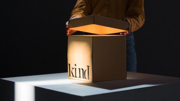 Young ethnic woman opening cardboard box standing on table